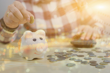 money, home, finance and relationships concept -man with pig bank sitting on desk,Businessman putting coin into the piggy banks,vintage color morning light