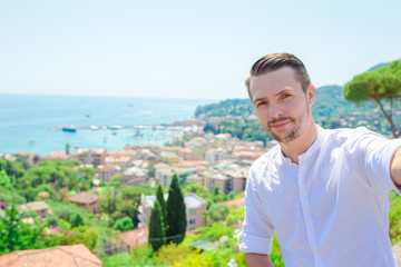 Fototapeta na wymiar Happy young man taking selfie background the old coastal town of old italian city in Liguria