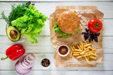Hamburger with beef, french fries and vegetables on wood table. Top view. Flat lay.