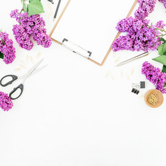 Blogger of freelancer workspace with clipboard, scissors, lilac flowers and accessories on white background. Flat lay, top view