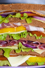 Tall sandwich with beef cheese pork tomato black background