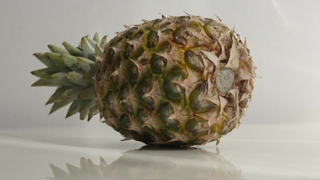 Fresh exotic pineapple on white slow tilt 4K 2160p 30fps UltraHD footage - Ananas comosus tropical fruit close-up 4K 3840X2160 UHD tilting video