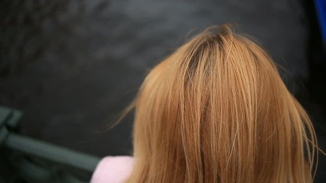 A woman in a coat stands on a bridge and looks down at the black water. She wants to commit suicide