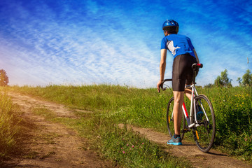 Naklejka premium Young bicyclist riding in the field