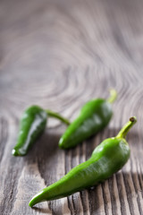 Three green hot peppers on a wooden table