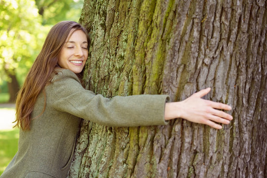 Young woman hugging trunk of tree