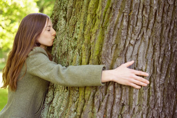 Young woman hugging and kissing tree