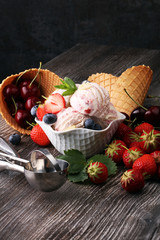 Strawberry ice cream in white bowl with fresh strawberries and b