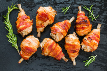 Bacon wrapped chicken drumsticks on a black stone background, top view. - 160963949