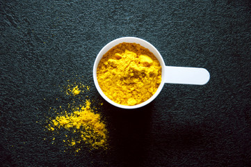 a cup with yellow spice on the black background