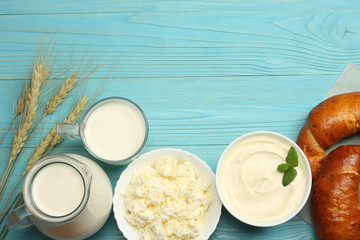 Milk background. Glass jug pitcher of fresh milk with glass, sour cream, cottage cheese and eggs on blue wooden background. Top view with copy space.