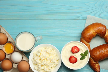 Milk background. Glass jug pitcher of fresh milk with glass, sour cream, cottage cheese and eggs on blue wooden background. Top view with copy space.