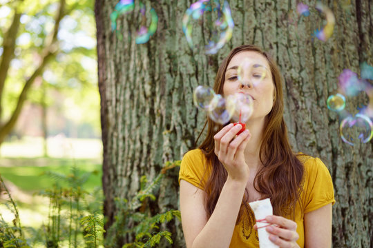 Young woman blowing iridescent soap bubbles