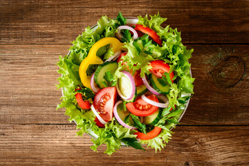 Fresh vegetable salad with greens on wooden table.