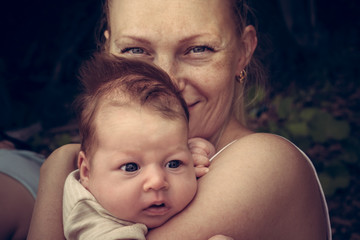 Mother sincerely hugging her newborn baby. Conceptual picture symbolizing baby care and love