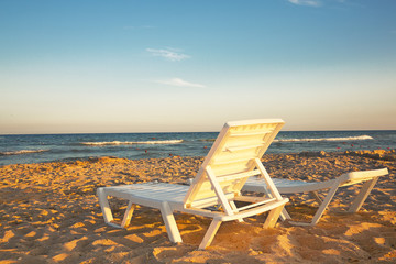 Two deckchairs on the sandy beach