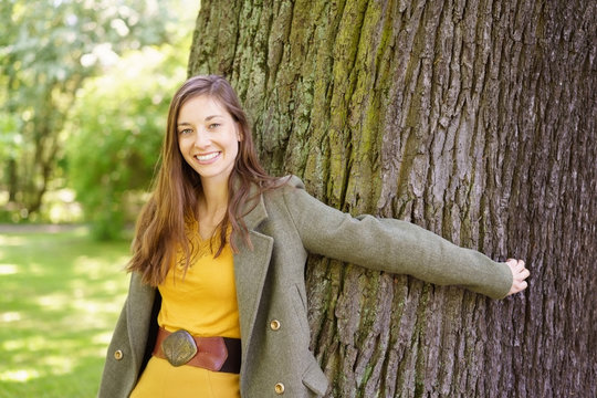 Smiling woman with her arms around a tree