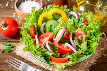 Fresh vegetable salad with greens on wooden table.
