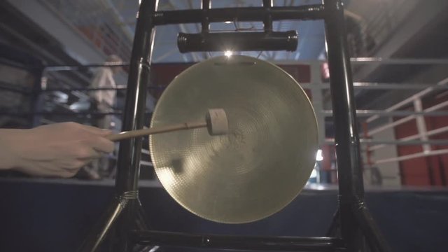 Native gong Hand with hammer banging a native golden gong.
