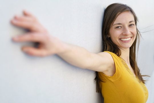 Happy woman at white wall with arms aside