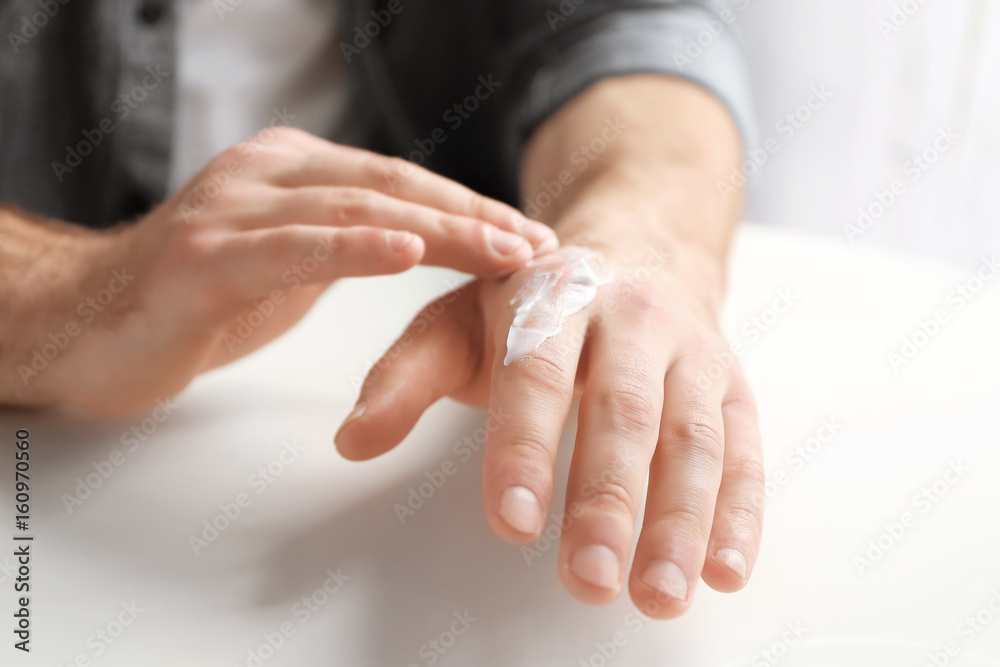 Wall mural man applying cocoa butter lotion onto hand over table