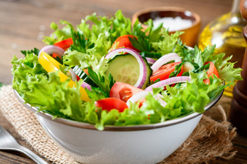 Fresh vegetable salad with greens on wooden table.
