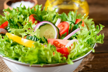 Fresh vegetable salad with greens on wooden table.