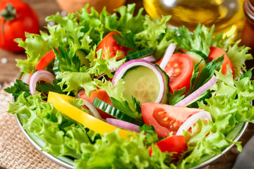 Fresh vegetable salad with greens on wooden table.