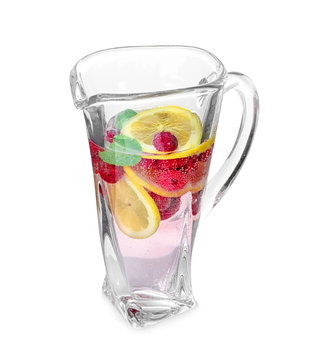 Tasty refreshing lemonade with berries and mint in glass jug on white background