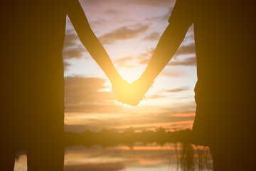 Couple holding hands a watching a beautiful sunset