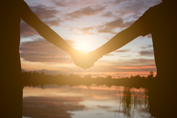 Couple holding hands a watching a beautiful sunset