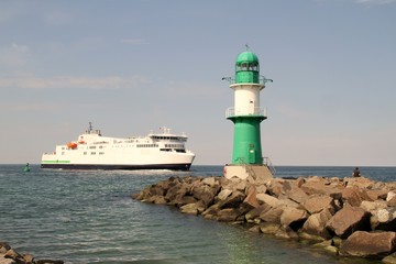 Obraz premium Grünweißer Leuchtturm mit Fährschiff in Warnemünd