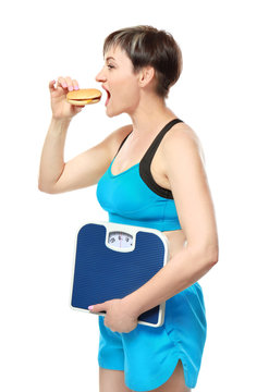 Mature woman with scales and hamburger on white background. Weight loss concept