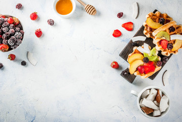 Breakfast. Homemade fresh Belgian soft wafers with honey, fruits, nuts, berries - peach, blackberries, raspberries, strawberries, coconut, cashews, strawberries, mint. Light table. Copy space top view