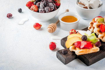 Breakfast. Homemade fresh Belgian soft wafers with honey, fruits, nuts, berries - peach, blackberries, raspberries, strawberries, coconut, cashews, strawberries, mint. Light table. Copy space