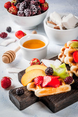 Breakfast. Homemade fresh Belgian soft wafers with honey, fruits, nuts, berries - peach, blackberries, raspberries, strawberries, coconut, cashews, strawberries, mint. Light table. Copy space