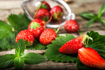 Fresh strawberry with mint lies on a wooden table background. Food in the macro.