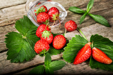 Fresh strawberry with mint lies on a wooden table background. Food in the macro.