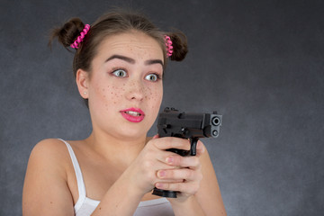 fun girl aiming with gun on gray background