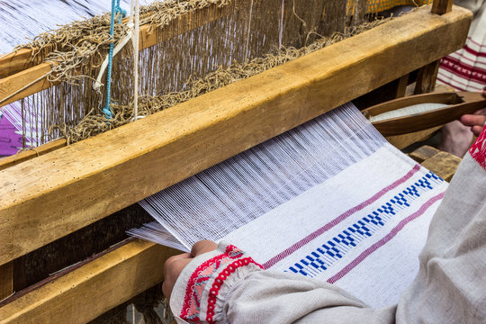 Woman weaving traditional slavic linen on horizontal loom