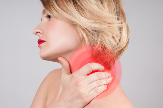 Young woman with neck pain, massaging her shoulder