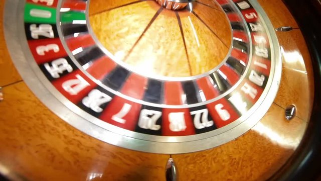 Wooden colourful classic casino roulette. Casino machine and gambling equipment. Roulette table with chips next to the roulette. Spinning roulette in motion.