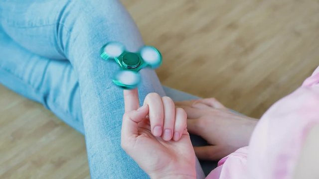 Girl playing with a glossy light colourful Hand Spinner toy