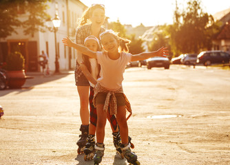 Mother plays with her daughters on the street in the neighborhood. They drive rollerblades. Family...