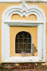 Window with an arch of white and grating on the background of beige wall