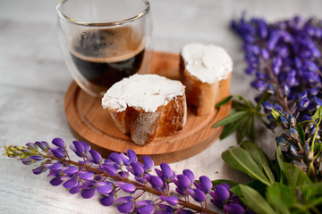 coffee mug served with bruschetta on a wooden Board and lupins flowers on the table