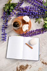 Note with a pen, a calendar and a Cup of coffee served with bruschetta, lupins flowers on wooden table