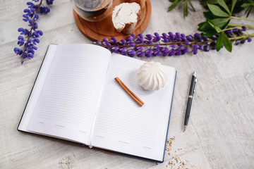 Note with a pen, a calendar and a Cup of coffee served with bruschetta, lupins flowers on wooden table