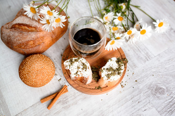Cup of coffee served with biscuits and buns on wooden background