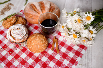 Cup of coffee served with biscuits and buns on wooden background